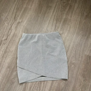 Mönstrad omlottkjol - Snygg och stilren omlottkjol med ett diskret mönster. Perfekt för både vardag och fest! Kjolen har en tight passform och är i en kort modell. Den är i ett mjukt och bekvämt material som gör den skön att bära hela dagen.