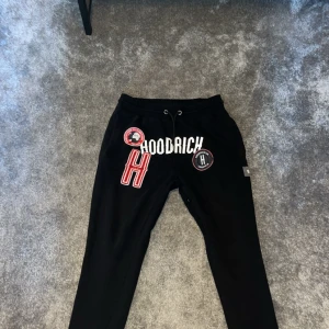 Svarta mjukisbyxor från Hoodrich - Säljer ett par svarta mjukisbyxor från Hoodrich. De har coola tryck och broderade detaljer på framsidan. Byxorna har en snörning i midjan för bästa passform. Perfekta för en avslappnad stil eller chill dagar hemma. 🖤