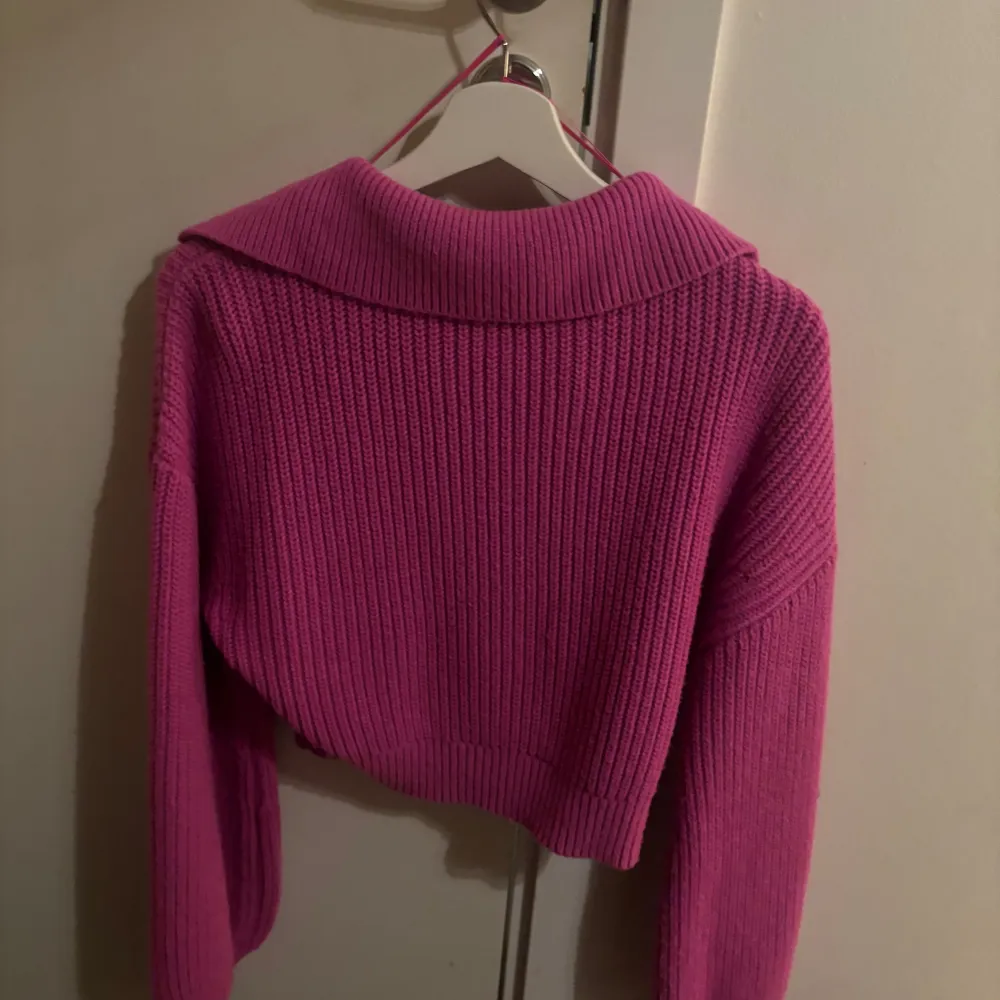 Säljer en superfin rosa stickad tröja från Zara. Den har en snygg v-ringning och en krage som ger en stilren look. Perfekt för höst och vår! Tröjan är croppad och har långa ärmar, vilket gör den både trendig och bekväm. Passar perfekt till jeans eller kjol. 💖. Tröjor & Koftor.