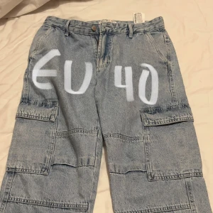Grå cargopants i denim - Säljer ett par grå cargopants i denim. De har flera praktiska fickor och en loose passform som ger en avslappnad stil. Perfekta för vardagsbruk eller en casual utflykt. Byxorna är i bra skick och redo för nya äventyr!