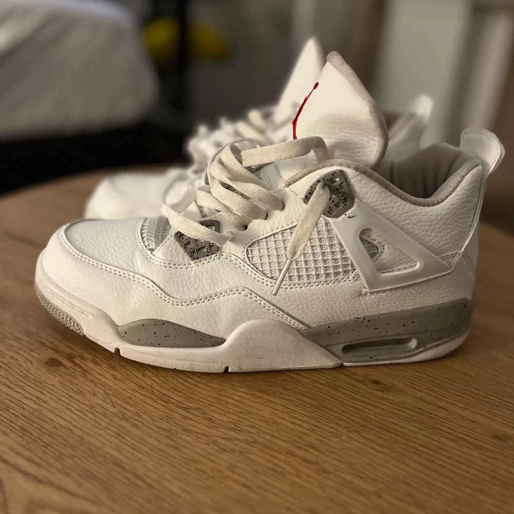 Säljer ett par snygga vita Nike Air Jordans med grå detaljer och röd logga. Skorna har en cool design med snörning och är i nyskick. Perfekta för både vardag och fest! 🏀. Skor.