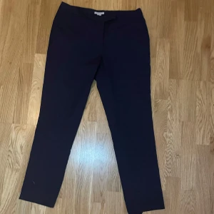 Mörkblåa kostymbyxor - Säljer ett par mörkblåa kostymbyxor från H&M i storlek 40. De är stilrena och passar perfekt för både vardag och fest. Byxorna har en tight passform och är gjorda i ett bekvämt material. 