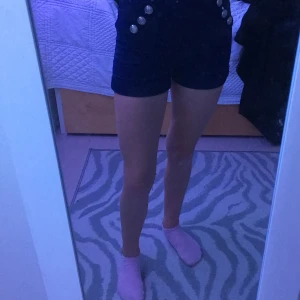 Shorts stl. xs - Detta är ett par shorts. Dom är marinblå med silver knappar på, har även en dragkedja i bak.