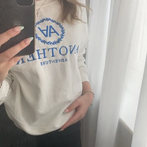 Vit collegetröja med blå broderi  - Tröjan är liten i storlek och kort, men är 160 och den passar mig och detta är en L