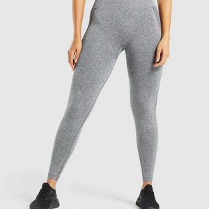 Gymshark flex high waisted leggings - Snygga gråmelerade träningsleggings från Gymshark som tyvärr ej kommer till användning. Byxorna har mörkare partier (contour) längs sidan av benen samt omkring rumpan. Tjockt tyg men samtidigt sjukt strethiga och bekväma att ha på sig! 