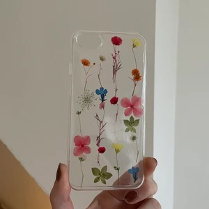 Blommigt-silikonskal till iphone 8 - Detta är ett helt nytt mobilskal med motiv av riktiga torkade blommor. älskar modellen, funkar framförallt till iphone 8 men går säkert till en iphone sju eller sex också. Jag säljer det för att företaget skickade mig fel storlek men ska köpa ett nytt som är likadant till min mobil. orignal pris = 120kr. Jätte bra kvalité och sitter bra runt kanterna på mobilen. (köparen står för frakten🌟🌟🌟💫🤝)