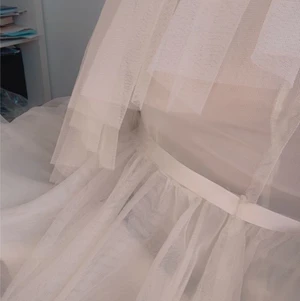 Aurora Dress Ida Sjöstedt  - Aurora Dress Ivory från Ida Sjöstedt, vit miniklänning i tyll med vit snöre vid midjan som är justerbart. Klänningen är så gott som ny och helt oanvänd, prislappen är kvar.