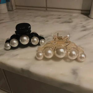 Genomskinliga hårklämmor med pärlor - Köpte två av fel storlek så säljer dom. Kan köpas separat eller så kontakta mig för paketpris! 6cm så ganska små funkar om du använder för halva håret. Ena är helsvart med pärlor den andra är transperant champagnefärgad. Jättefina har själv den större varianten. Piffar upp håret mycket! Pris Exkl Frakt 
