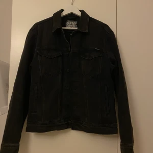 Jeansjacka  - Jeansjacka från superdry. Köpte den från killavdelningen i storlek L för ville ha den lite oversize. Den är urtvättad svart färg. Nästan aldrig använd. Köparen står för frakten 55 kr. För fler bilder är de bara att skicka meddelande. 