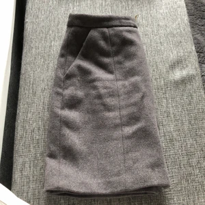 Grå ”ull”kjol. - Grå kjol med imitation av ull från Vero Moda. Guldig dragkedja framtill. Storlek S. Använd fåtal gånger. Enbart tvättad i fintvätt. Katt finns i hemmet. 