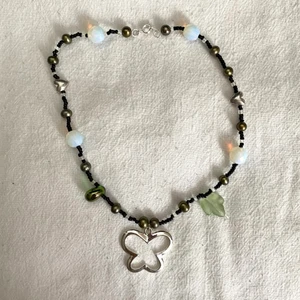 Pärlhalsband med fjäril - Fjärilshalsband i svarta och gröna pärlor 🌸 har en stängning så oelastiskt snöre. Väldigt fairycore om jag får säga det själv. Köparen står för halva frakten 