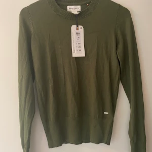 Oanvänd grön stickad tröja m. gulddetalj - Perfekt grön färg inför för hösten. Helt ny och oanvänd! Hade gärna behållt själv  men den är för liten. Passar till allt och superskönt material🍃🍃