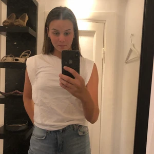 Vit T-shirt  - En armlös vit T-shirt, vad mer kan man begära? Nej men en verkligen super cool T-shirt som med bara en enkel detalj piffar upp det vardagliga! Storlek XS men passar även mig som oftast har S i plagg! Sparsamt använd och det finns inga defekter på plagget!