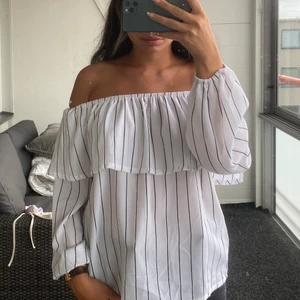 Randig blus - Vit offshoulder blus med svarta linjer. Köpt utomlands så har ingen aning om vart den kommer ifrån men använd endast fåtal gånger. Köpten står för eventuell frakt💕