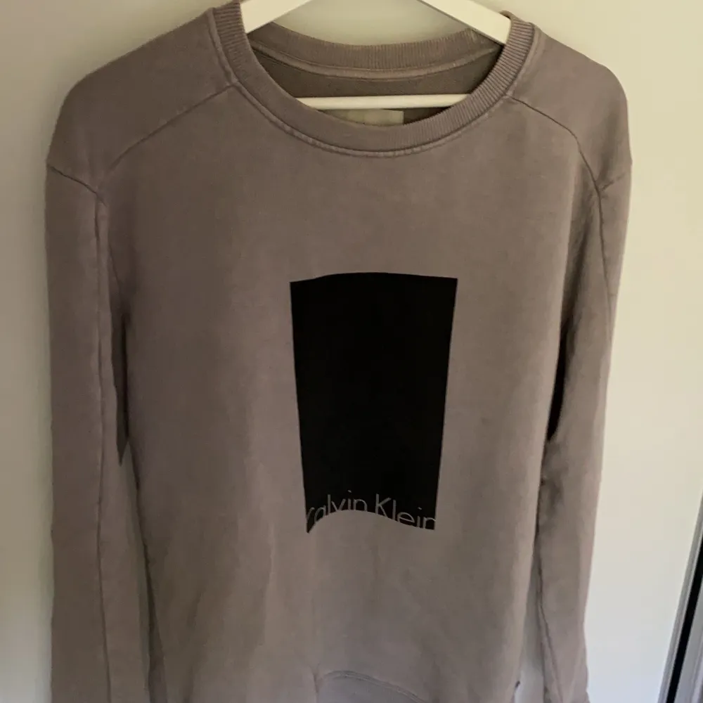 Stengrå sweatshirt med svart tryck på magen från Calvin Klein Jeans. Använd 5 gånger och inköpt förra året. Strl L och passar mig perfekt som är 188/78kg. . Tröjor & Koftor.