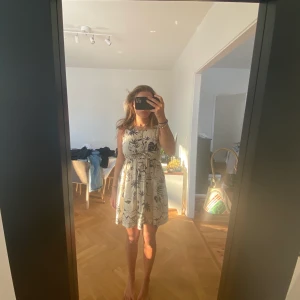 Vit klänning med svart mönster - Den här så söta klänningen är vit med ett svart mönster på sig, den är även öppen i ryggen och har en liten rosett som man ser på bilden, så fin att ha på sig nu när det börjar bli sommar, det går även bra med leverans men köparen står för kostnaden av frakten💖