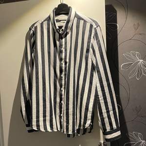 Svart/vit randig skjorta med lång ärm från Casual Friday. Köpt från Zalando i april 2020 för ca. 500kr. Mycket bra skick och sparsamt använd. Storlek M, passar M/L. Skriv privat för mer bilder. Köparen står för frakt