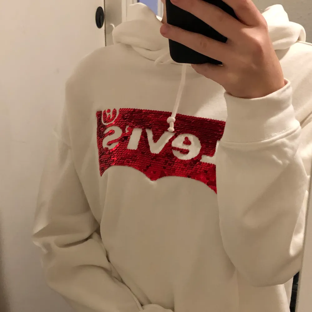 En vit croppad Levis hoodie med vändbara paljetter! Använd en enda gång och är i mycket fint skick! Hoodiens ordinarie pris är 650kr.  🤍🥥🦢. Hoodies.