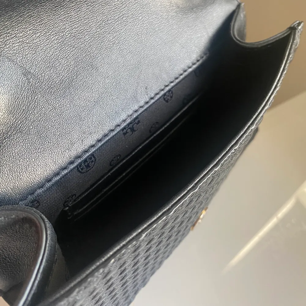 Säljer denna svarta Tory Burch mini bag med guldiga detaljer. Är använda men fortfarande i gott skick! Man kan välja att ha det som en crossbody bag eller korta ner kedjan och ha den på ena axeln. Finns även små kort fack inne i väskan. Säljer den för 250kr😊. Väskor.