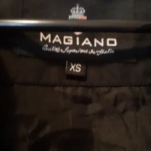 Magiano jacka - En fin svart jacka med volanger längs dragkedjan på framsidan. En jacka du både kan klä upp och ha som vardagsjacka. 😀