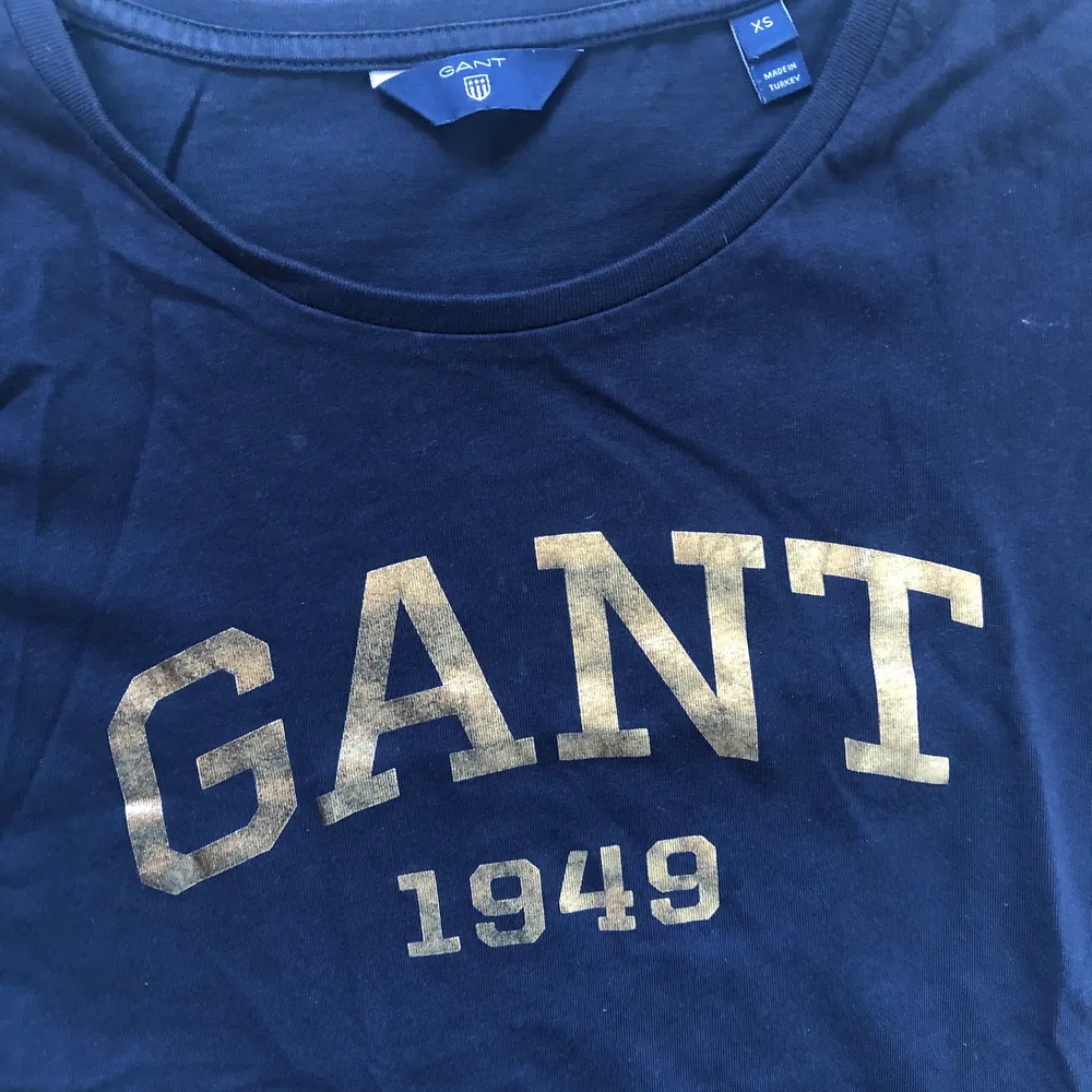 Fin marinblå t-shirt med guldtryck från Gant. I storlek XS. . T-shirts.
