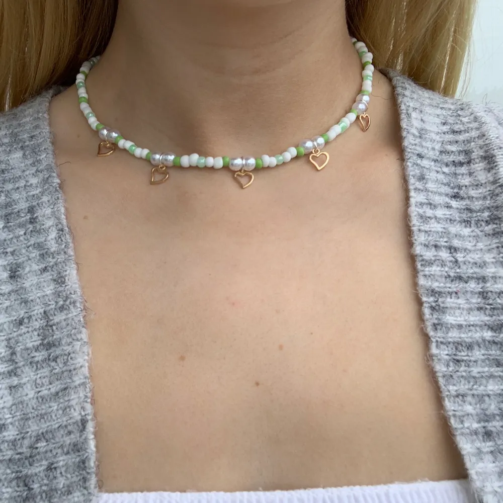 Vitt och grönt pärlhalsband med små söta guldhjärtan 🤍💚⭐️💕🤩 halsbandet försluts med lås och tråden är elastisk . Accessoarer.