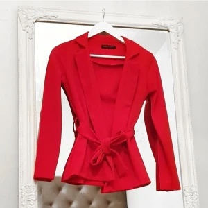 Röd XS-S belted blazer kavaj jacka - Färg: röd.  Strl: XS-S.  Material: 95% Polyester 5% Elastane.   Fin blazer, endast använd vid ett tillfälle. Som ny! Hyskor för medföljande band, eventuellt annat skärp. Passar både vardags och fest. Betalning via swish, frakt tillkommer.