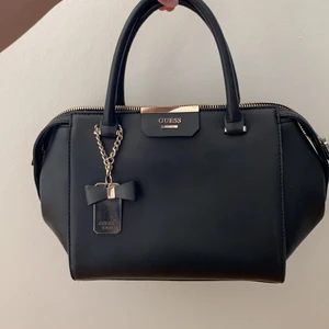 Guess väska - Väska ifrån guess i svart🎉🎉aldrig använd och är därmed i nyskick. Tillhörande ”förlängningsband” tillkommer. Skriv för frakt kostnad❤️ köpt för 1600 o säljer för 750