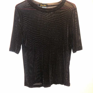Glitter-top - Fin T-shirt i svart lite genomskinligt glittertyg. På mig som är storlek S är den oversize, så passar även en M-L om du vill ha tightare. Köpt utomlands.