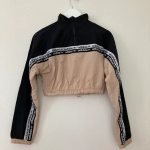 Adidas tröja - En tröja från adidas i ett tunt prassligt material. Den har en dragsko i midjan och en dragkedja i kragen så att man kan öppna den om man vill eller inte.