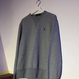 Herr Polo Ralph Lauren college-tröja - Sparsamt använd colleage tröja. Lite ljusare grå i verkligheten men marinblå häst detalj. Storlek herr L men lite liten i storleken. Buda i kommentarerna, från 200 kr