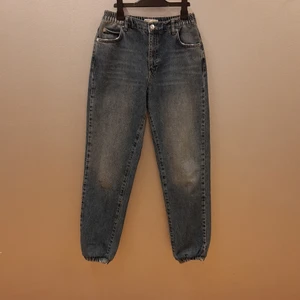 Mom Jeans från ginatricot i stl 38 - Säljer dessa "joggar mom jeans" från ginatricot i stl 38. Jeansen har hög midja och blixtlåsgylf. De har även resår i såväl midja och nedtill (se bild 3). Jeansen är nya och oanvända men säljes då de är för stora för mig.