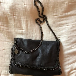 Stella McCartney inspirerad väska - BUD JUST NU: 300kr + frakt!                                             Säljer denna Stella McCartney inspirerade väska då den inte kommer till användning! Köpt för några år sedan men endast använd fåtal gånger, därför i bra skick! De enda defekterna på väskan är att metallknapparna inuti har små slitningar samt att Stella McCartney taggen också har små slitningar! Hör av dig om du vill ha fler bilder på väskan☺️