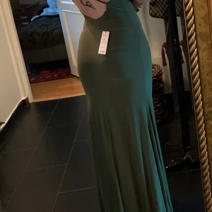 Oanvänd balklänning - Köpte denna till balen 2018 men användes aldrig då jag hittade en annan. Har legat i garderoben sedan dess och har lapparna kvar. Storlek 14 och är jätteskön och stretchig. Jag har vanligtvis storlek 10-12 men denna passar mig jättebra. Den är väldigt lång men är säkert lätt att lägga upp om det behövs! 