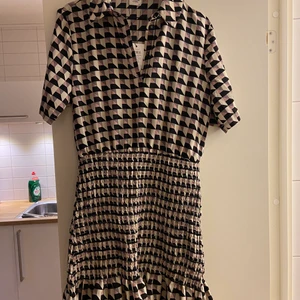 Rutig klänning - Säljer denna rutiga klänning med resor runt midja/rumpa som ger kroppen en snygg figur. Klänningen har knappar mellan brösten. Aldrig använd! Från Jacqueline de Young i storlek 38💗