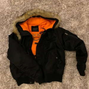 Svart vinterjacka med päls - Hej! Säljer denna svarta vinterjacka med en ”fake” päls! Jackan är perfekt för kyla då den värmer bra! Orange i insidan och i Storleken M. Få gånger använd eftersom inte riktigt min stil, tyvärr. Därför säljer för endast 150kr! Köpt inne i JC från märket CROCKER ❤️ Frakten är spårbar 🥰