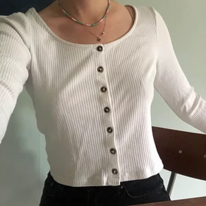 Vit långärmad tröja  - Vit långärmad tröja från monki, knäppningen fram går att öppna så man kan även ha det lite mer uppknäppt ;) Den är något croppad, går typ dit högmidjade byxor går! Gott skick! 