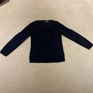 En mörk blå blus/tröja med fina detaljer.