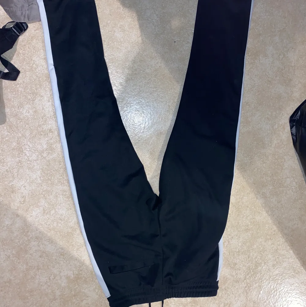 Svarta finare mjukisbyxor från herravdelningen på H&M med en vit rand på sidan av benen. Dragkedja en bit i slutet av benen. Nypris 199kr. Använda fåtal gånger, sparsamt. . Jeans & Byxor.