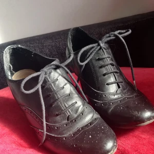 Snörskor med klack, storlek 40 - Ett par klackade snörskor i Oxford-stil, 70-tals inspirerade. Storlek 40. Fina spetsdetaljer framtill och även på sidorna, sula i äkta läder på insidan. Bekväma men lite slitna, se bilder. Snörningen hjälper till att garantera snygg och skön passform. De har mycket kvar att ge!  Finns i Stockholm eller skickas mot frakt, 66:-. Bara att fråga om fler bilder, kan ej lägga upp alla här 🌷