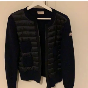 Moncler cardigan - Mörkblå Moncler maglione tricot alla coreana i storlek S. Mycket bra skick förutom ett hål vid armbågen när jag råkat fastna i något, säkert lätt att fixa. Nypris ligger på typ 6200kr. Har ej kvitto men man kan se att den är äkta med hjälp av koden på lappen! 
