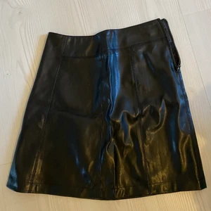 Kjol i fakeläder - Kjol i fakeläder, fint skick. Dragkedja i sidan. Köparen står för frakt. 