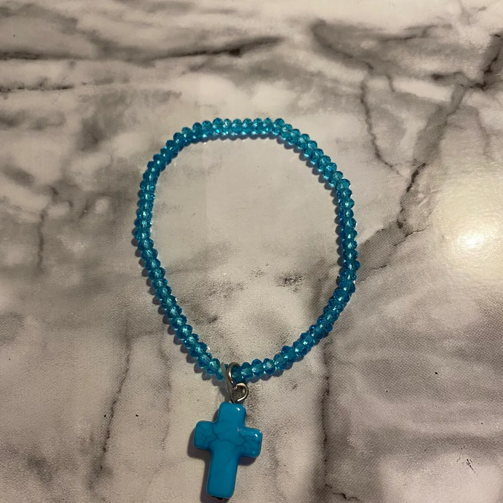 Gulligt blått armband med ett kors. Accessoarer.