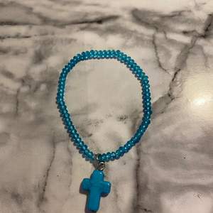 Gulligt blått armband med ett kors