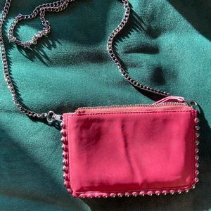 Mörkröd väska med nitar  - Stilren och cool axelväska med nitar och avtagbar kedja från Zara. Väskan har två olika nyanser av rött på de två sidorna vilket ger en fin variation där du kan välja den sidan själv som passar bäst med din outfit. Väskan har tre fack varav det mittersta går att stänga. Nästintill oanvänd och modellen finns inte kvar längre. Mitt pris 90kr. Högsta bud just nu: 110kr ❤️