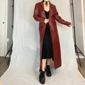 Skinnkappa - Supersnygg röd-brun läderkappa i toppenskick. Från Auluna Leather Company. 100% läder. Storlek 36. Modellen använder vanligtvis storlek S/M och är 169cm för referens. Många av knapparna är lösa! Även diskret ”klädmärke” på baksidan. Mått -   Ärmlängd 60cm, midjebredd 44cm och längd från axeln och ner 135cm 