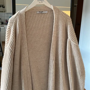 Lång stickad kofta - Superfin lång stickad kofta från NA-KD. Den är beige med en svag rosa ton och passar till det mesta. Ganska ”tung” passform som faller snyggt. Säljer en likadan i svart. Bra skick!! Hör av dig med frågor eller prisförslag!🤍