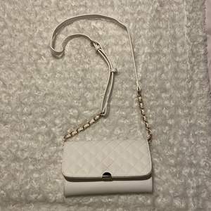 Här en en söt, liten, vit handväska som passar perfekt att ha mobilen och läppglanset i. Använd en gång på balen i nian så den är i nyskick❤️ Detaljerna är i guld och bandet är långt men har gjort ett eget hål så den funkar även som axelväska😍 