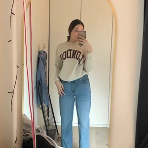 Beige hoodie  - Beige hoodie med svart och röd text 