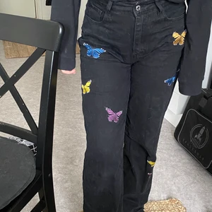 Svarta jeans med fjärilar - Supergulliga svarta jeans med färgglada fjärilar på!! ”Klippta” nertill vilket ger lite fransar! Mjukt material så de är även sköna! Storlek L men passar även M! I bra skick! Köparen står för frakten (66kr) 🥰! 